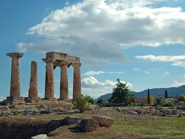 ancient ruins with tall columns standing in a field under a cloudy blue sky