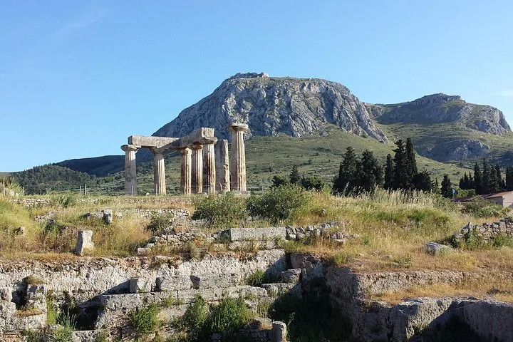 ancient ruins with tall columns and a large mountain in the background under a clear sky