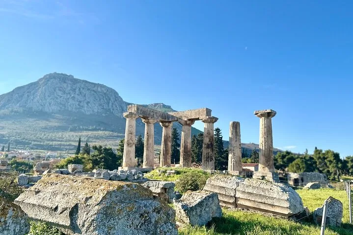 ancient ruins with columns and a large rocky mountain in the background
