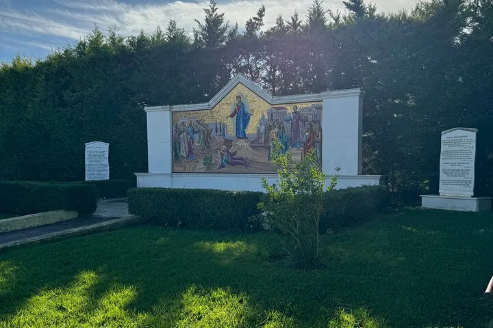 a mosaic depicting a religious scene on a wall in a garden setting