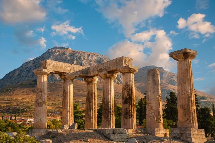 ancient ruins with tall columns and a large mountain in the background at sunset