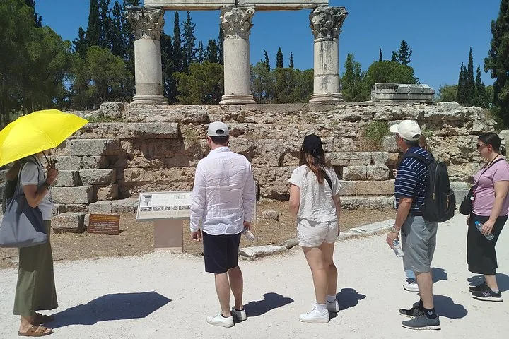 a group of tourists listening to a guide in front of ancient ruins