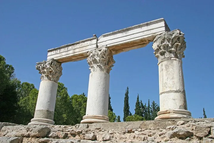 ancient ruins with three tall columns and an architrave under a clear blue sky